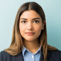 Closeup of young female professional making eye contact against colored background